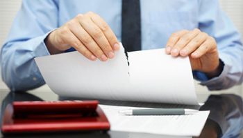 A man in a blue shirt and tie is holding a piece of paper